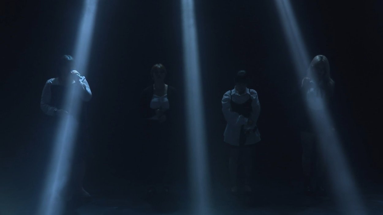 온맘씨어터 프리즘 미니콘서트 — 어두운 무대 위 네 줄기 조명 아래 선 출연자 4명의 단체 무대